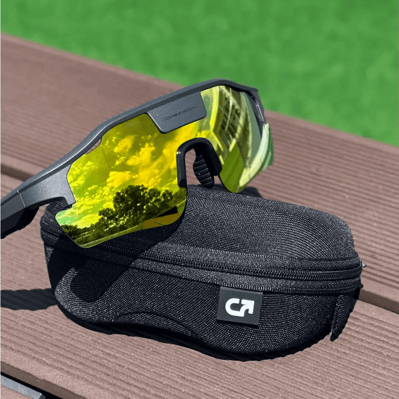 Cybersight Zenith with gold lenses and black case on a wooden surface with green grass in the background